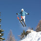 Kind springt beim Skifahren über einen Baumstumpf