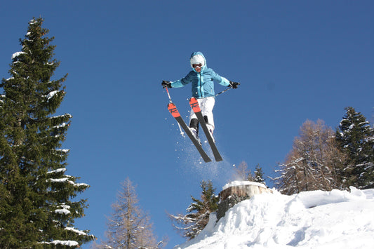 Kind springt beim Skifahren über einen Baumstumpf